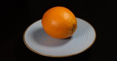 Siyah arkaplanda seramik bir tabakta portakalın yakın plan çekimi.