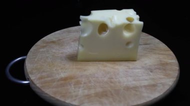Tahtadaki siyah arkaplanda bir parça peynir..