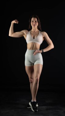 Beyaz spor kıyafetleriyle poz veren güzel genç bir kadın.