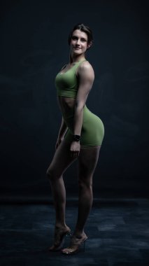 Siyah elbiseli genç bir kadın. Siyah arka planda poz veren siyah fotoğraflı bir kadın. figür