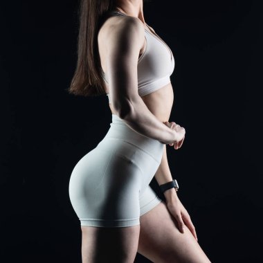 Beyaz spor elbiseli güzel bir kadın siyah arka planda poz veriyor.