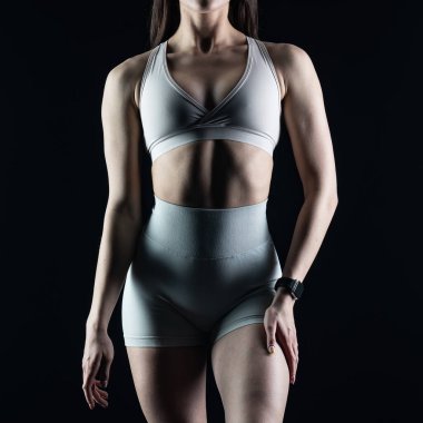 Stüdyoda gri arka planda poz veren mükemmel vücutlu genç bir kadın.