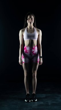 Stüdyoda siyah arka planda poz veren genç bayan sporcu