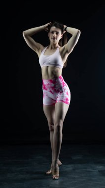 Stüdyoda poz veren genç ve güzel bir kız, gri arka planda duruyor.