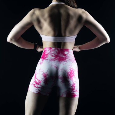 Stüdyoda pembe arka planda poz veren genç bir kadın.