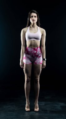 Stüdyonun arka planında pembe iç çamaşırlı güzel bir kadın var. uygun vücut.
