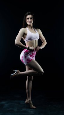 Siyah bir arka plan önünde egzersiz yapan genç bir kadın..