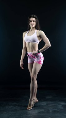 Gri bir stüdyonun önünde poz veren genç bir kadın.