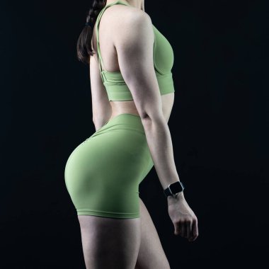 Siyah bir arka planda siyah spor kıyafetleri içinde mükemmel vücutlu güzel bir fitness kızı.