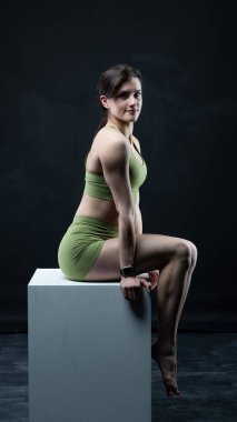 Stüdyoda siyah arka planda poz veren genç ve güzel bir kadın.