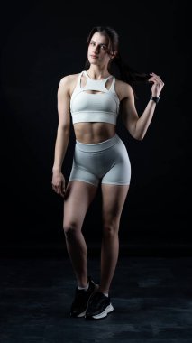 Beyaz spor kıyafetli kadın halterle poz veriyor..