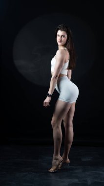 Siyah arka planda beyaz iç çamaşırlı genç bir kadın.