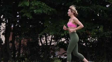 Parkta egzersiz yapan, esneme hareketleri yapan bir kadın.