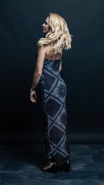 Stüdyoda poz veren seksi uzun elbiseli genç kadın.