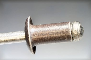 Metal perçin ve metal eklemlerin konsepti olarak gri eğimli arka planda çekiş pimi olan henüz işlenmemiş çelik levha kör perçine aşırı yakın çekim