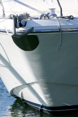 Güvenilirlik ve güvenilirliği limana bağlayan bir gemi konsepti olarak metal çapalı beyaz bir motorlu yatın ön yayı kısmen görülüyor.