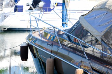 Şamandıra ile marinada soylu lüks motorlu tekne arka planda diğer gemilerin önünde ram koruması olarak deniz ve su sporları tatilinde dinlenme konsepti olarak kullanılıyor.