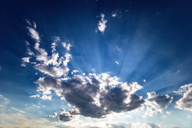 Güzel mavi gökyüzü, beyaz bulutlar ve güneş ışınlarıyla