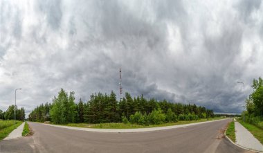 Arka planda orman ve seyyar kule antenli yağmur bulutlarının görüntüsü, yol manzarası.