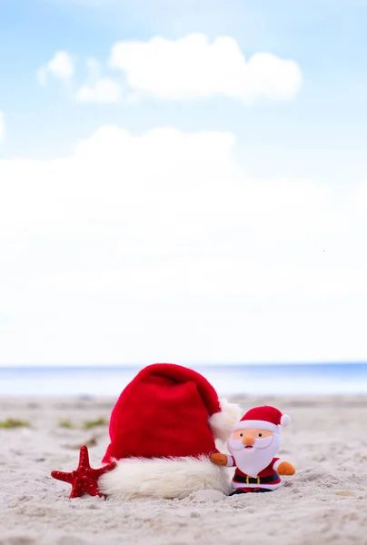 Christmas background. Santa Claus hat,starfish and Santa toy on sandy beach.Christmas card and advent calendar concept. Travel ticket sale concept for christmas holidays.Copy space.High quality photo
