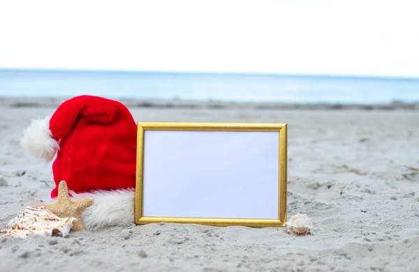 Christmas vacation at sea. Santa Claus hat, starfish, frame rate for text on sandy beach.Christmas card and advent calendar concept. Travel ticket sale concept for christmas holidays.Copy space.Close