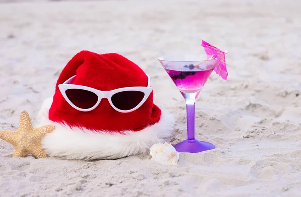 Christmas vacation at sea. Happy New Year holidays. Santa hat, starfish, sunglasses,coctail on sandy beach.Christmas card and advent calendar concept. Travel ticket sale concept for christmas holidays
