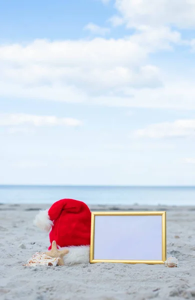Christmas vacation at sea. Santa Claus hat, starfish, frame rate for text on sandy beach.Christmas card and advent calendar concept. Travel ticket sale concept for christmas holidays.Copy space.Close