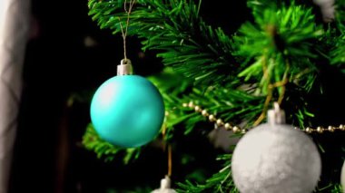Evdeki bir Noel ağacının dalında mavi bir Noel oyuncağı taşıyor. Yaklaş. Yavaş hareket. Yüksek kaliteli FullHD görüntüler.