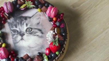 İçinde kedi resmi olan doğum günü pastası ve çilek, ahududu, yaban mersini, çikolata, badem kurabiyesi ile süslenmiş..