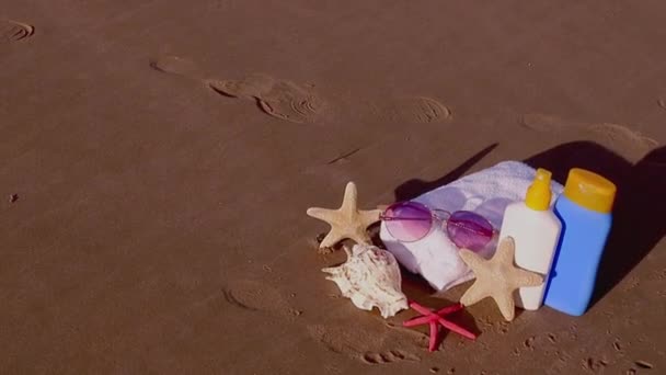 Sommerliche Hintergrundsonnencreme Muscheln Sonnenbrillen Strandtuch Und Seesterne Sandstrand Sommerferienkonzept Urlaubsreisekonzept — Stockvideo