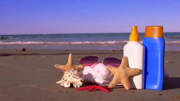 夏の背景の太陽のクリーム サングラス ビーチの白いタオル 貝および砂浜のヒトデ 高品質のフルHd映像 — ストック動画