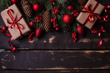 En üstteki fotoğrafta noel kutuları, kırmızı noel ağacı oyuncakları ve ahşap arka planda ladin dalları var. Metin için alanı olan Xmas arkaplanı. Kopyalama alanı.