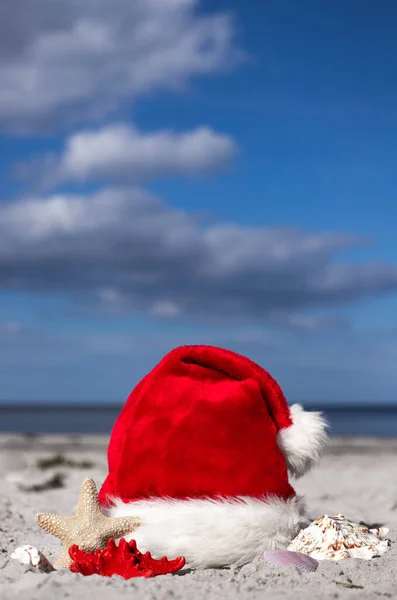 圣诞节的背景圣诞老人的帽子和海星在沙滩上 圣诞贺卡和日历的概念 圣诞假期的旅行票销售概念复制空间垂直摄影 — 图库照片