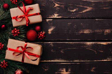 En üstteki fotoğrafta noel kutuları, kırmızı noel ağacı oyuncakları ve ahşap arka planda ladin dalları var. Metin için alanı olan Xmas arkaplanı. Kopyalama alanı.