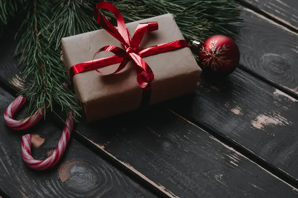 En üstteki fotoğrafta noel hediyesi kutusu, kırmızı noel ağacı oyuncakları, lolipoplar ve ladin brançı tahta zeminde. Boşluğu kopyala..