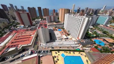 Benidorm şehrinin havadan görünüşü, İspanya. Binanın 18. katından deniz manzaralı caddeler, oteller, havuzlar ve gökdelenler. Yazın güneşli bir gün. Yüksek kaliteli FullHD görüntüleri.