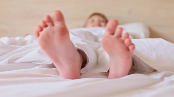 Μικρά Κοριτσίστικα Πόδια Ξεπροβάλλουν Κάτω Από Μια Λευκή Κουβέρτα Πρωί — Αρχείο Βίντεο