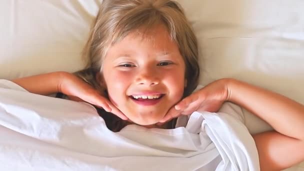 Κοντινό Γοητευτικό Χαρούμενο Κοριτσάκι Μακριά Μαλλιά Βρίσκεται Ένα Λευκό Κρεβάτι — Αρχείο Βίντεο