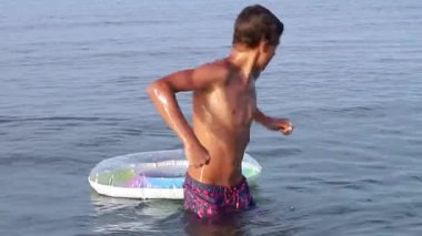Yavaş çekim ergen deniz suyunda şişirilebilir yüzme kucağına atlıyor. Yaz tatilinde genç kız suda eğleniyor. Aile tatilleri ve tatil konsepti. Yüksek kaliteli FullHD görüntüleri.