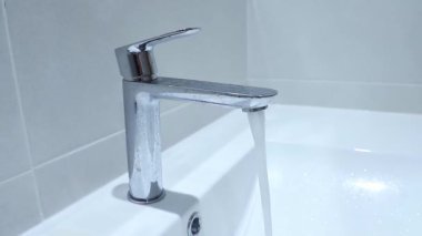 Musluktan beyaz banyo lavabosuna, yan görüş klipsine su akıyor. Yüksek kaliteli FullHD görüntüler