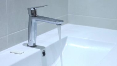 Temiz su musluktan beyaz banyo lavabosuna akar. Yüksek kaliteli FullHD görüntüler