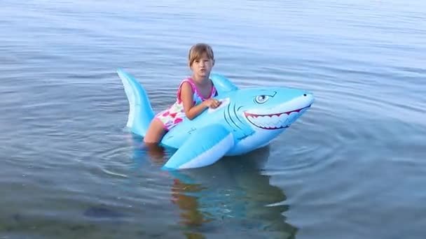 欧洲容貌7岁的快乐女孩在海里玩着一个充气的大鲨鱼玩具游泳 玩得很开心 家庭暑假和度假概念 优质Fullhd影片 — 图库视频影像