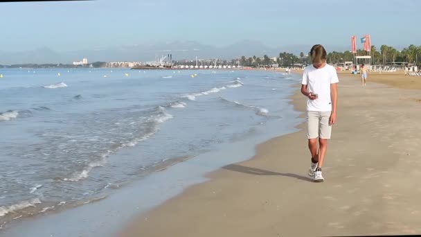 Handsome Teenager Boy Walks Seashore Using Smartphone Summer Weekend Vacation — Stock Video