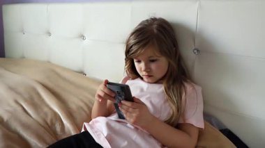 Sevimli küçük kız evde akıllı telefon kullanıyor, ağır çekimde. Yüksek kalite 4k görüntü