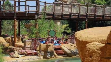 PORTAVENTURA DÜNYA, SALOU, SPAIN - 11 Haziran 2023: Salou İspanya 'daki Port Aventura World lunaparkındaki insanlarla su çekimi. İnsanlar ormanın içinde nehirde teknelerde yüzüyorlar.