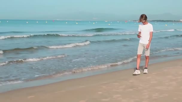 Handsome Teenager Boy Walks Coastline Using Smartphone Summer Weekend Vacation — Stock Video