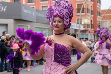 Colorful parade: hispanic adult female performing in lavish costume with purple fan on February 23, 2023 in Pilar de la Horadada,Spain . clipart