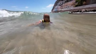 Güneşli bir günde, uçurumun kenarındaki sahilde neşeyle oynayan bir çocuk. Yüksek kaliteli FullHD görüntüler