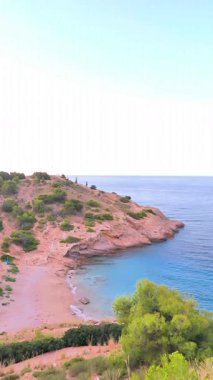 Kıyı manzarası kayalık araziden sakin sulara kademeli geçişi yakalar, doğanın canlı renklerini ve dokusunu vurgular.
