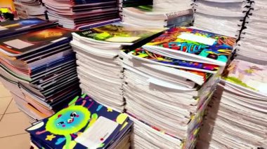 Riga, Letonya - 09 Ağustos 2022: Renkli defterlerden oluşan canlı bir koleksiyon, benzersiz tasarımlar ve dokular içeren bir kırtasiye mağazasında üst üste istiflenmiştir.